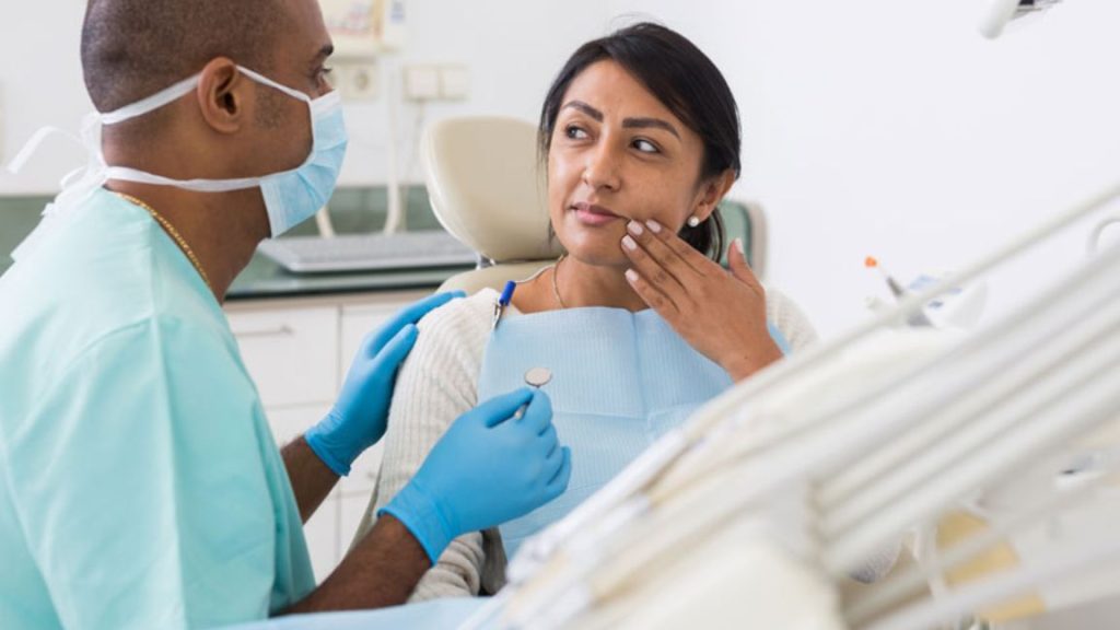 Woman Consulting With Dentist In Clinic
