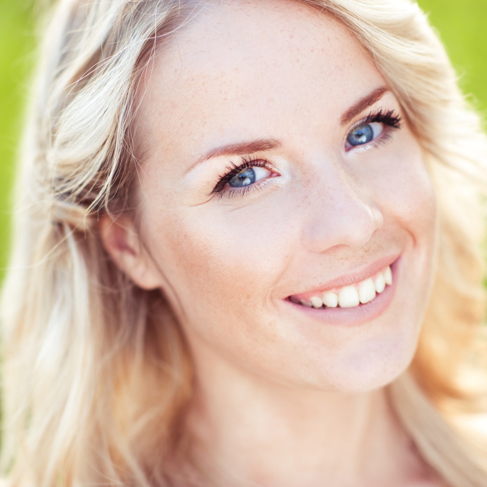 Beautiful blonde girl smiling outdoors. Looking at camera. Nature. Dental smile.