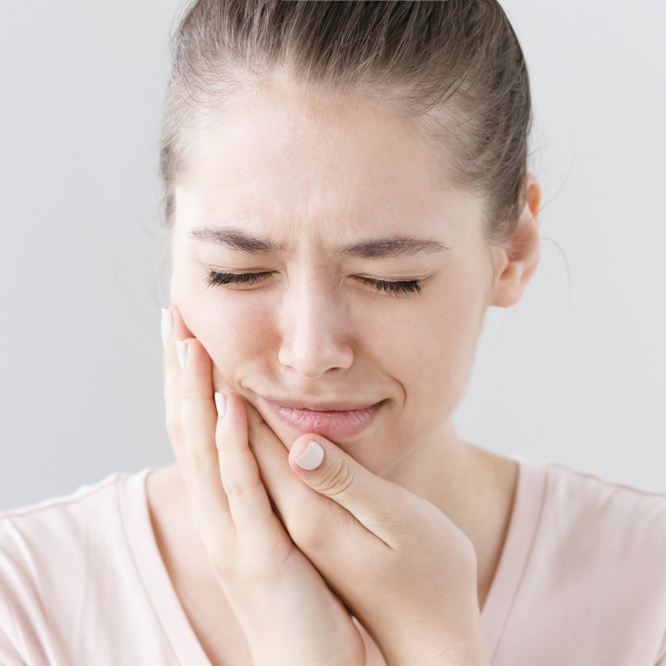 Closeup of beautiful teenage girl isolated on gray background touching her face and closing eyes with expression of horrible suffer from health problem and aching tooth showing dissatisfaction.