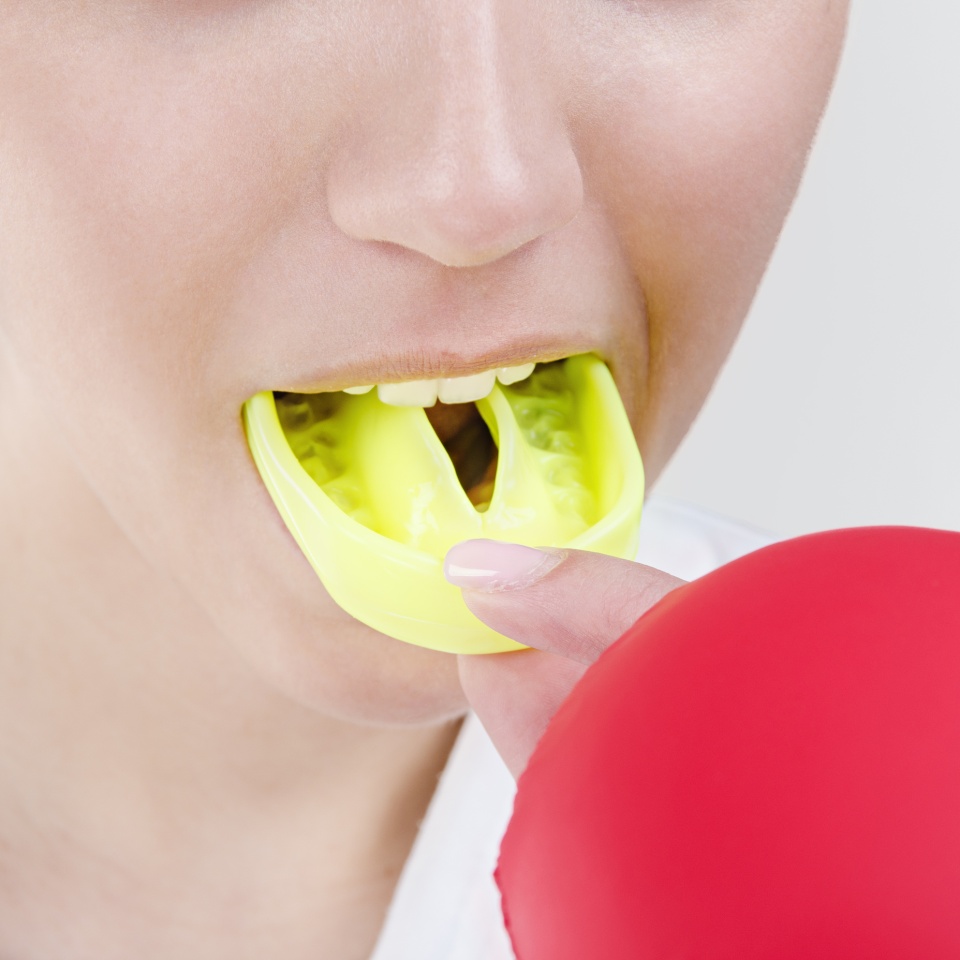 Young boxing woman using mouthguard. Studio shot
