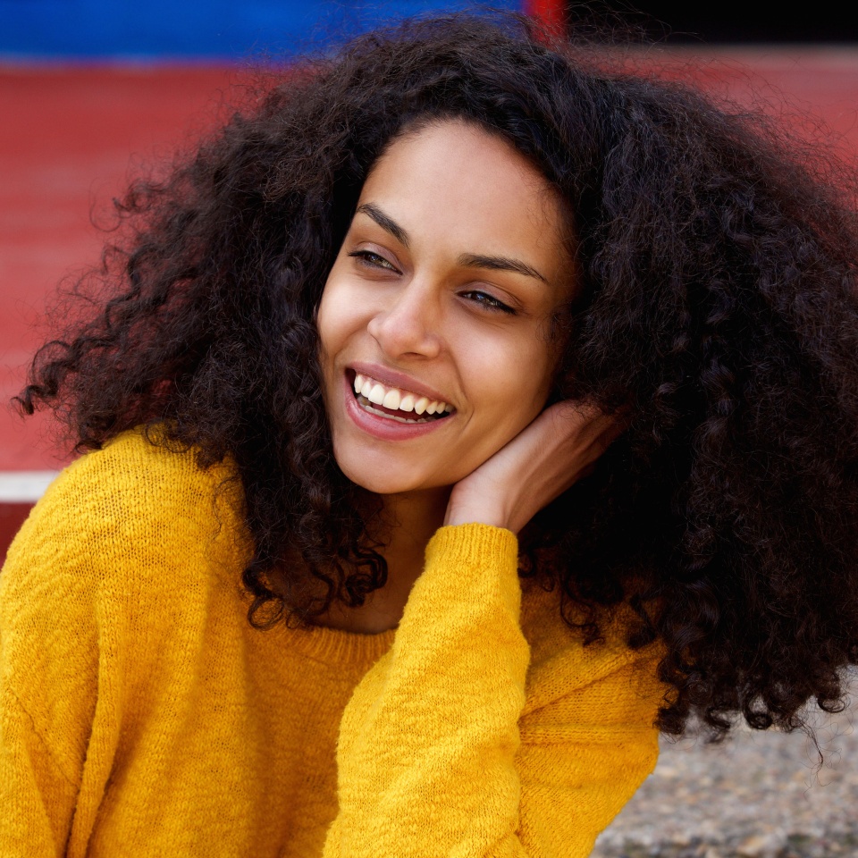 Close up portrait of young african lady with curly hair looking away and laughing