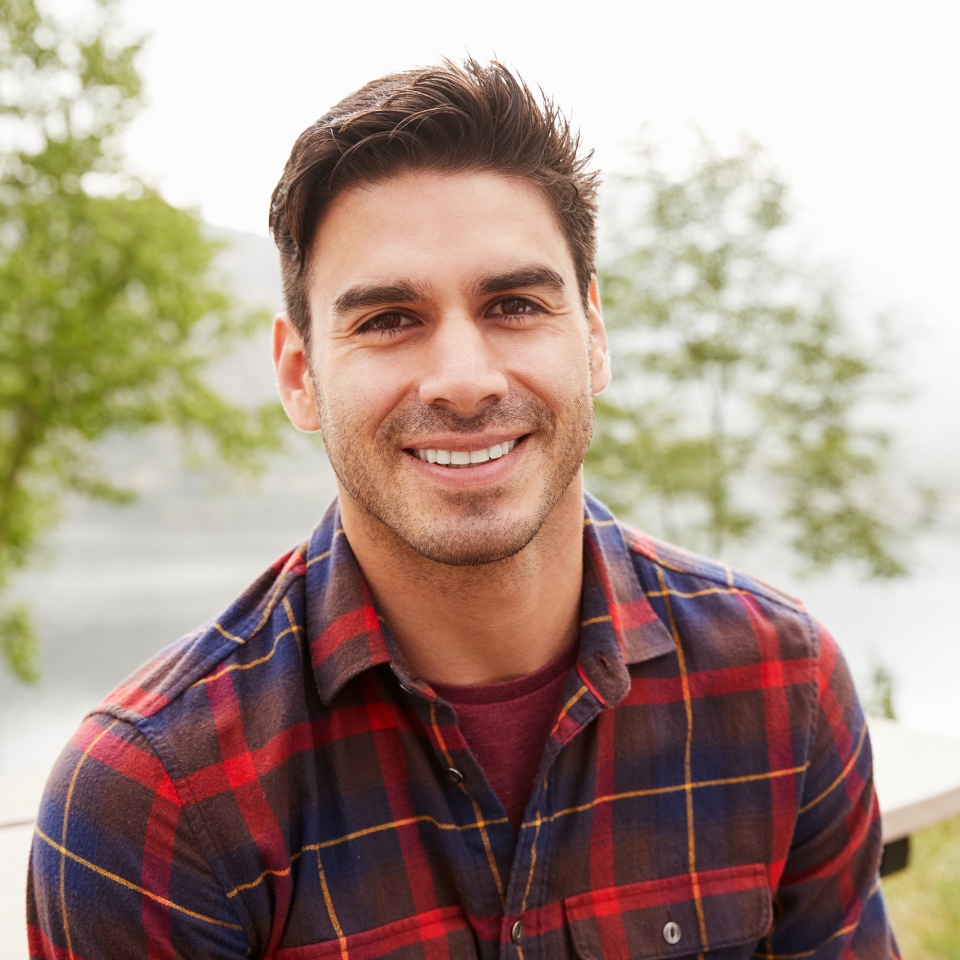 Young Hispanic man in a park smiling to camera, portrait