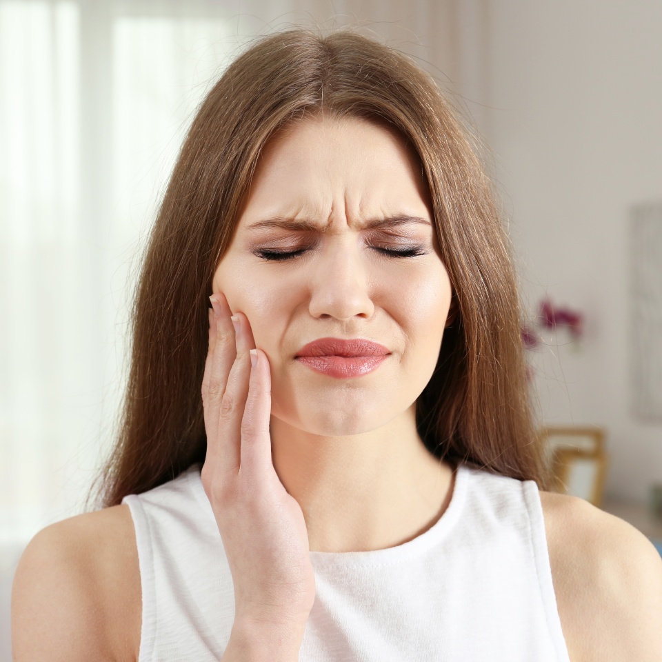 Young woman suffering from toothache at home