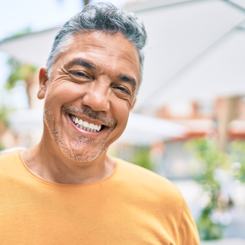 Middle age grey-haired man smiling happy walking at street of city.