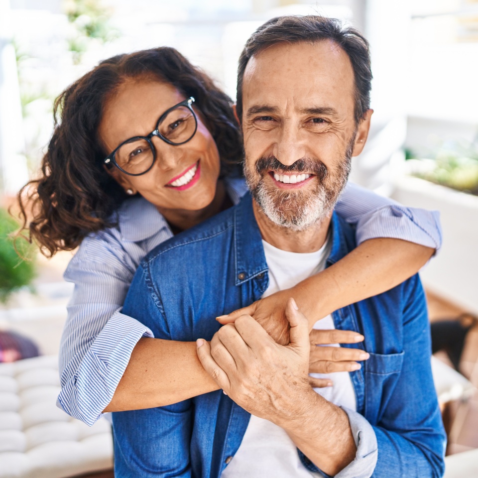 Middle age hispanic couple smiling confident hugging each other sitting on hammock at terrace