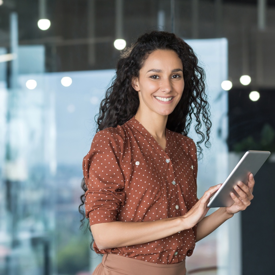 Young and successful female programmer, portrait of female engineer with tablet computer startup worker working inside office building using tablet for testing applications smiling looking at camera
