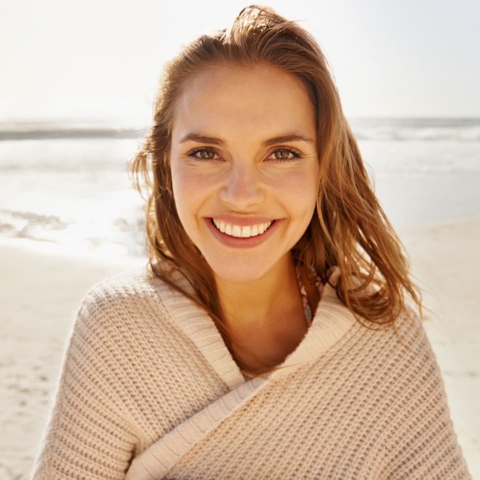 Travel, portrait and happy woman at a beach for summer, break or vacation, adventure or holiday. Ocean, face and female person smile at the sea with freedom, good mood or solo trip in South Africa