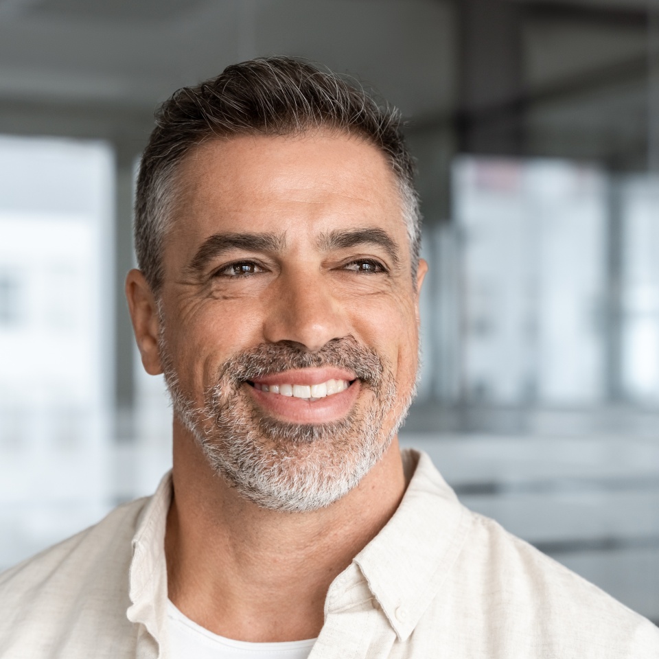 Headshot close up portrait of indian or latin confident mature good looking middle age leader, ceo male businessman on blur office background. Handsome hispanic senior business man smiling aside.