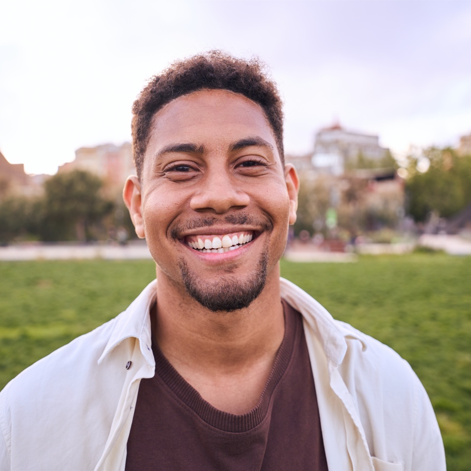 Handsome happy African American bearded man. Portrait of cheerful young man standing outdoors and smiling at camera. Positive emotion concept of male person. Generation z guy look carefree and natural