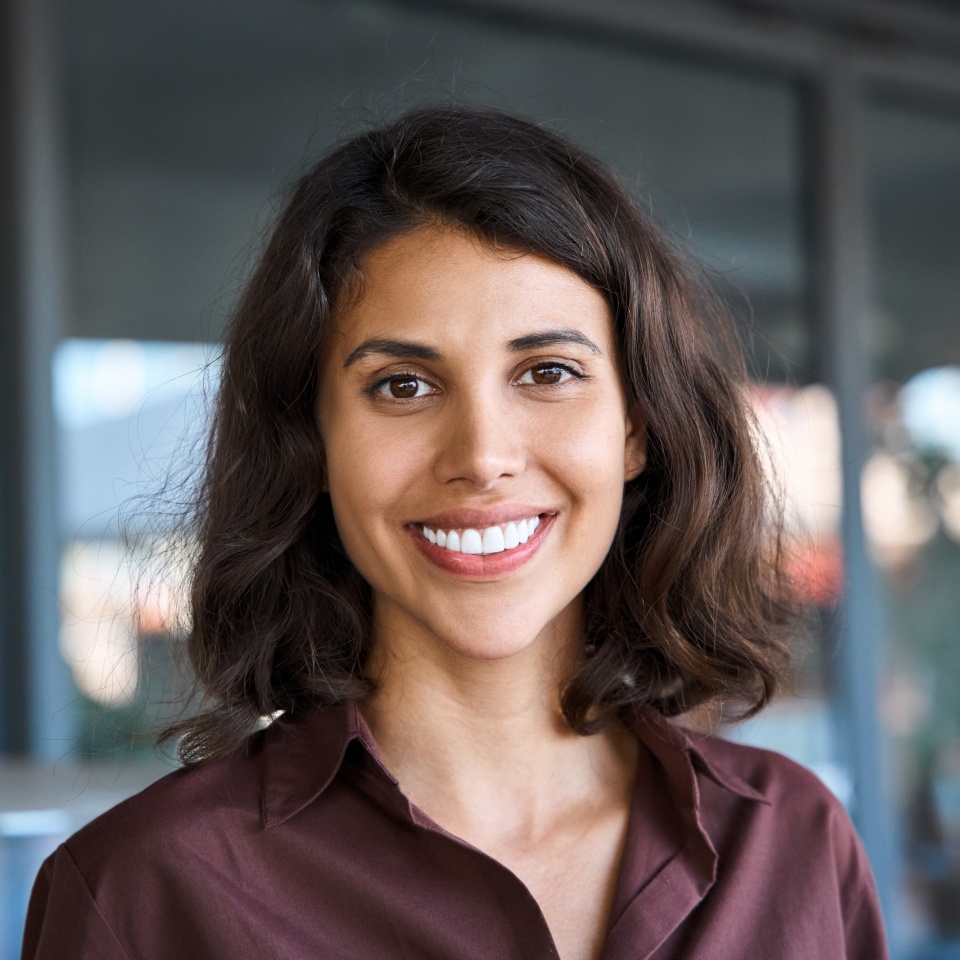 Closeup headshot face portrait of beautiful successful hispanic young business woman looking confident at camera. Smiling latin or eastern middle age female ceo leader businesswoman standing in office