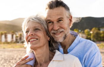 Beautiful happy senior couple dating at the seaside during summertime - Mature married couple in love bonding outdoors at the beach, concepts about elderly lifestyle, relationship and quality of life