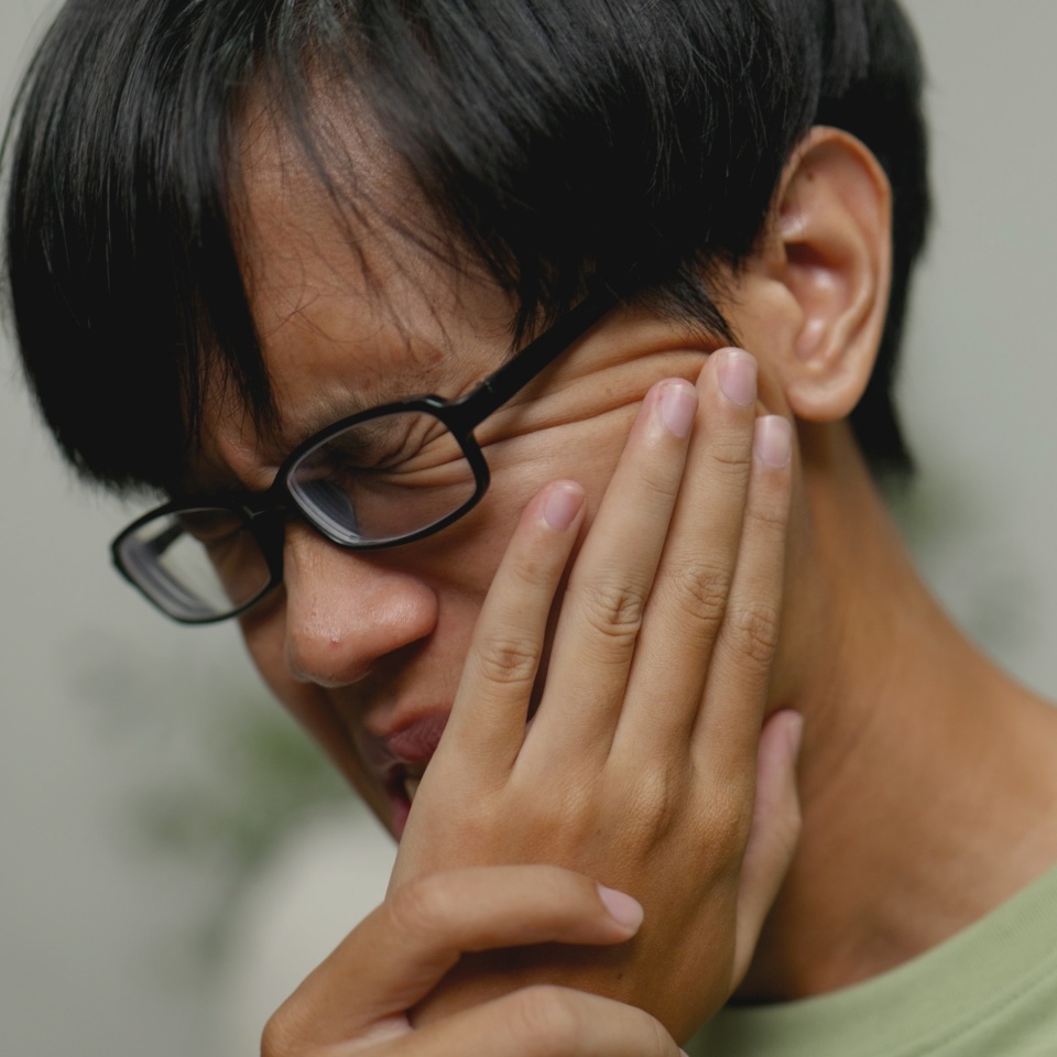 Asian man in severe toothache checking teeth with phone camera.