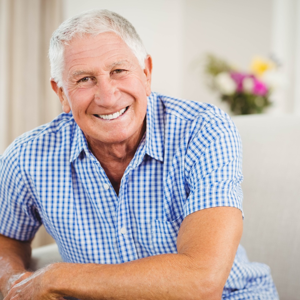 Senior man looking at camera and smiling in living room
